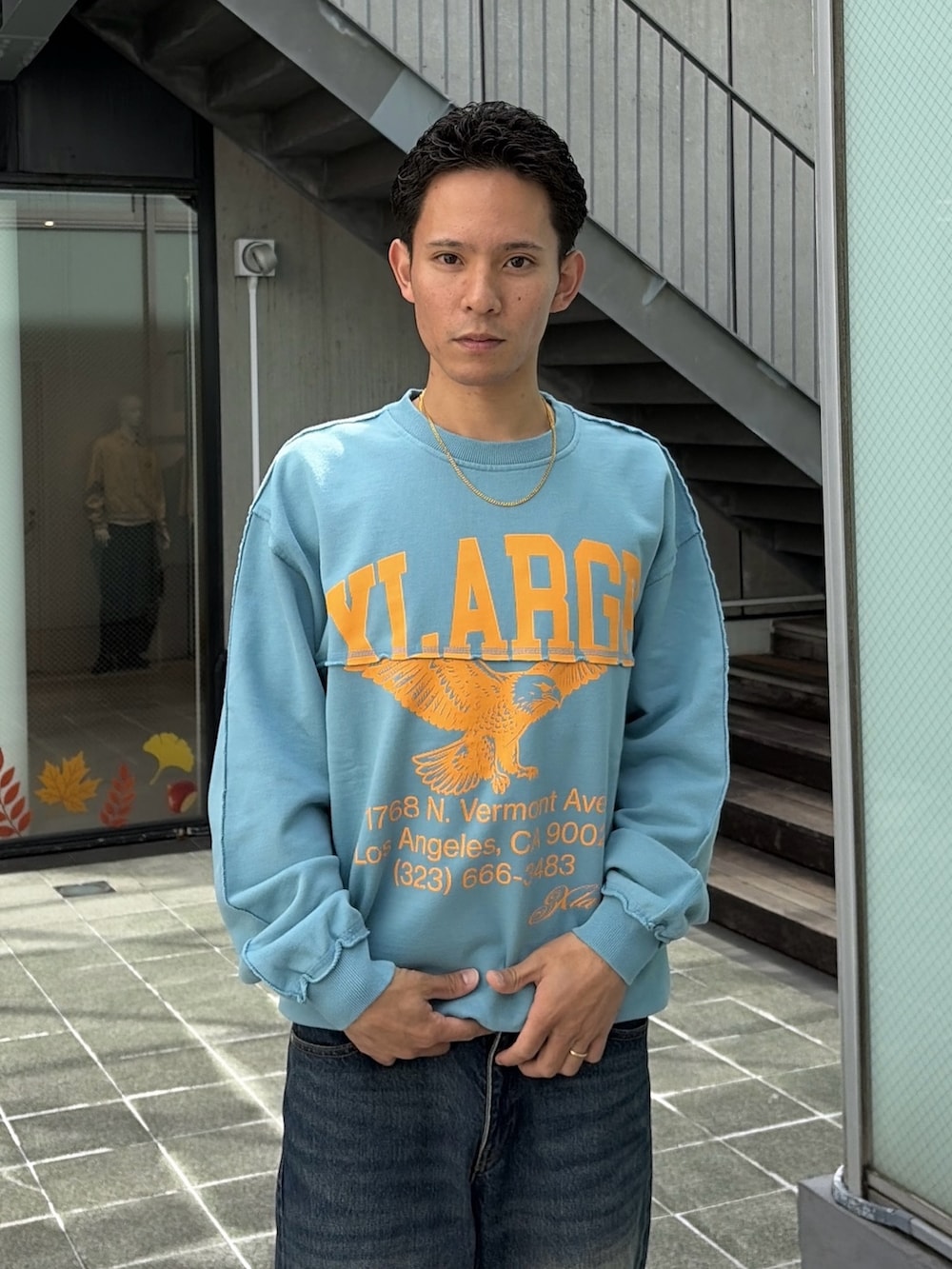 レッド系のナイロンジャケット、グレー系のスウェット、ブルー系のデニムパンツを着用したメンズの秋コーディネートの9枚目の写真