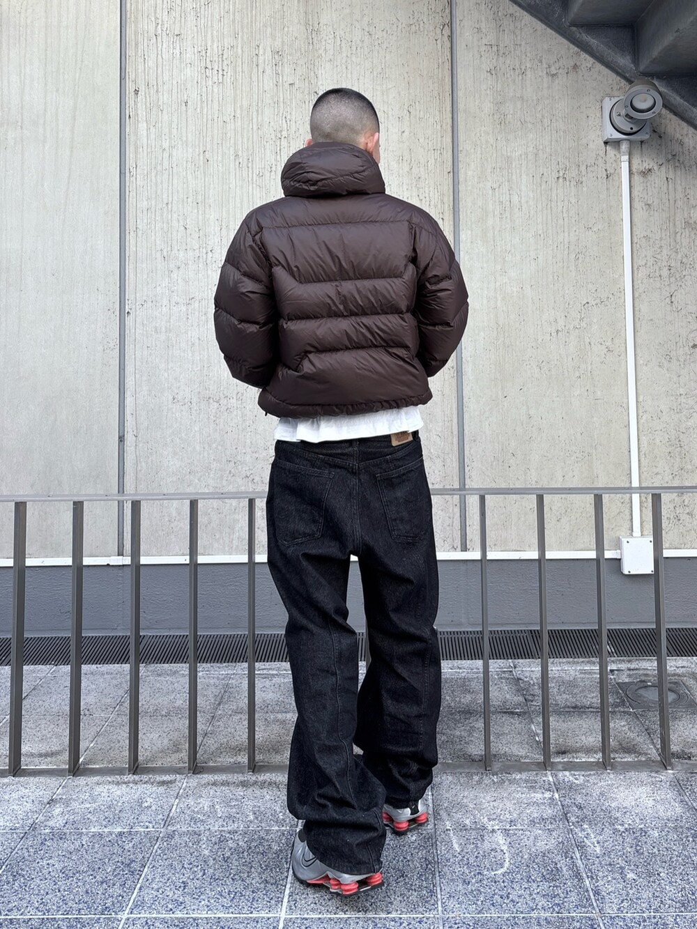 ブラウン系のダウンジャケット/コート、ブラック系のデニムパンツ、ブラック系の手袋を着用したメンズの秋コーディネートの4枚目の写真