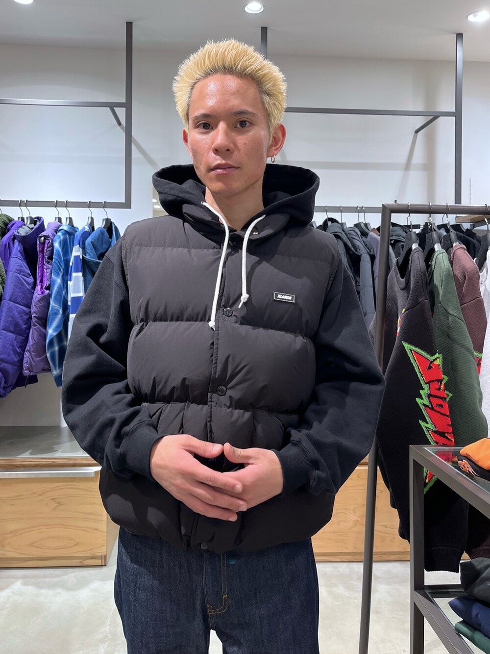 ブラック系のダウンベスト、ブラック系のパーカー、ブルー系のデニムパンツを着用したメンズの秋コーディネートの6枚目の写真