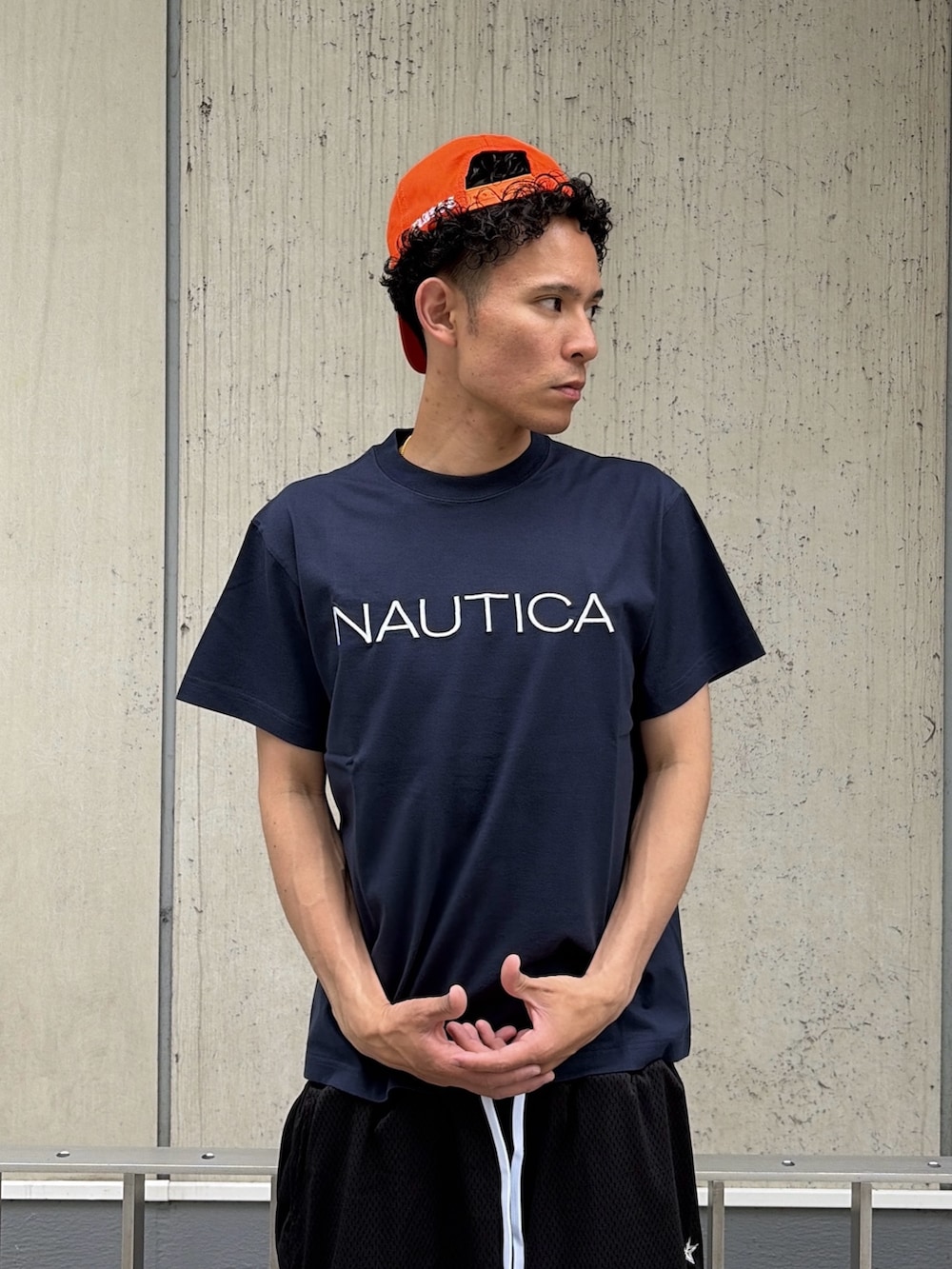 ブラック系のその他パンツ、ブルー系のTシャツ/カットソー、オレンジ系のキャップを着用したメンズの夏コーディネートの6枚目の写真