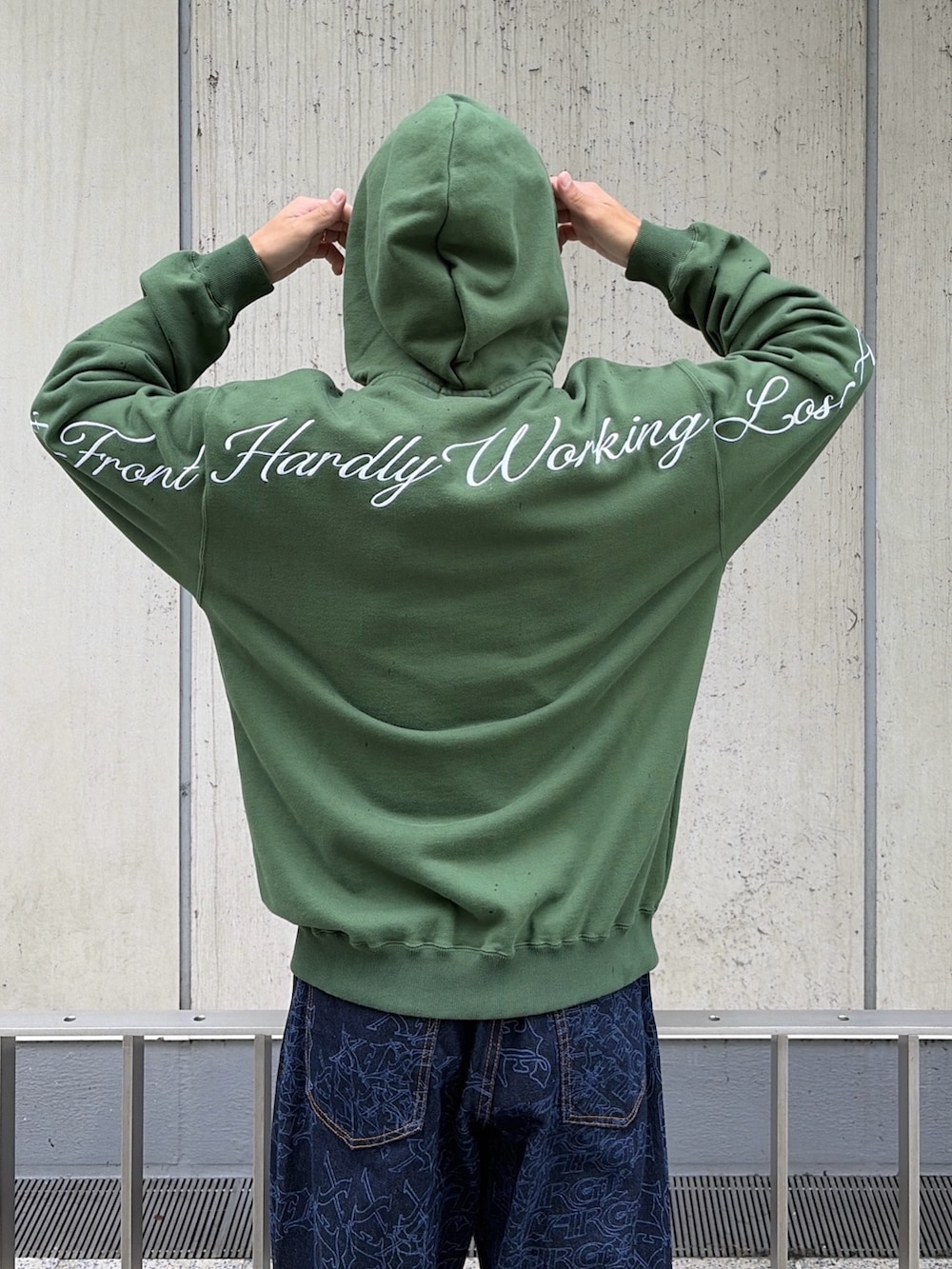 グリーン系のパーカー、ブルー系のデニムパンツ、レッド系のニットキャップ/ビーニーを着用したメンズの秋コーディネートの9枚目の写真