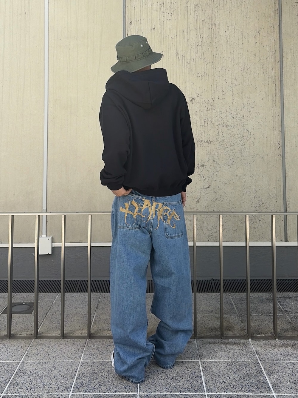 ピンク系のパーカー、ブルー系のデニムパンツ、ブラック系のハットを着用したメンズの春コーディネートの4枚目の写真