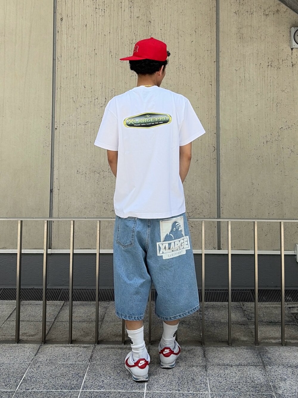 グリーン系のデニムパンツ、ホワイト系のTシャツ/カットソー、レッド系のキャップを着用したメンズの春コーディネートの4枚目の写真