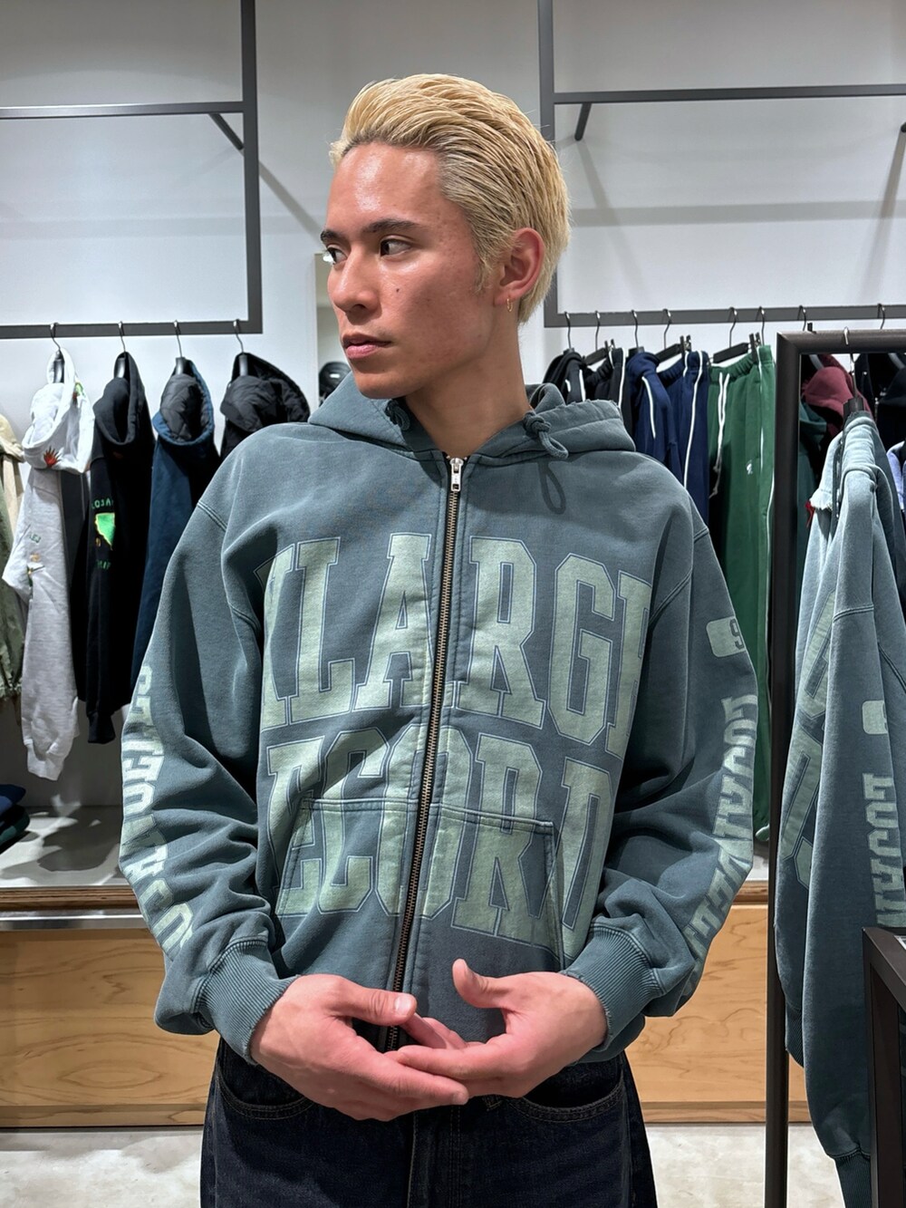 グリーン系のパーカー、ブルー系のデニムパンツを着用したメンズの冬コーディネートの5枚目の写真