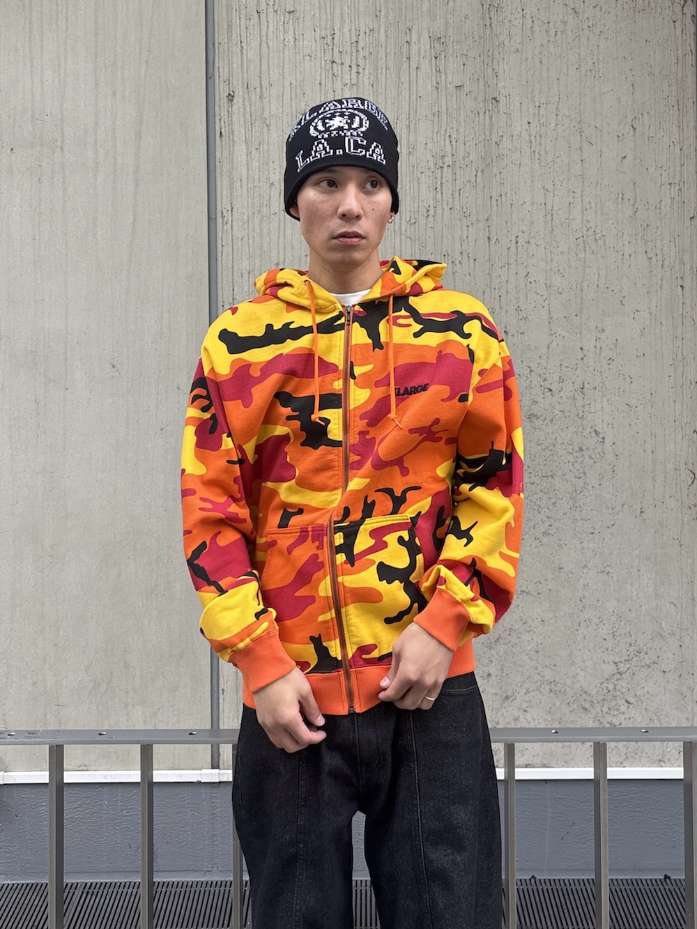 オレンジ系のパーカー、ブラック系のデニムパンツを着用したメンズの冬コーディネートの6枚目の写真