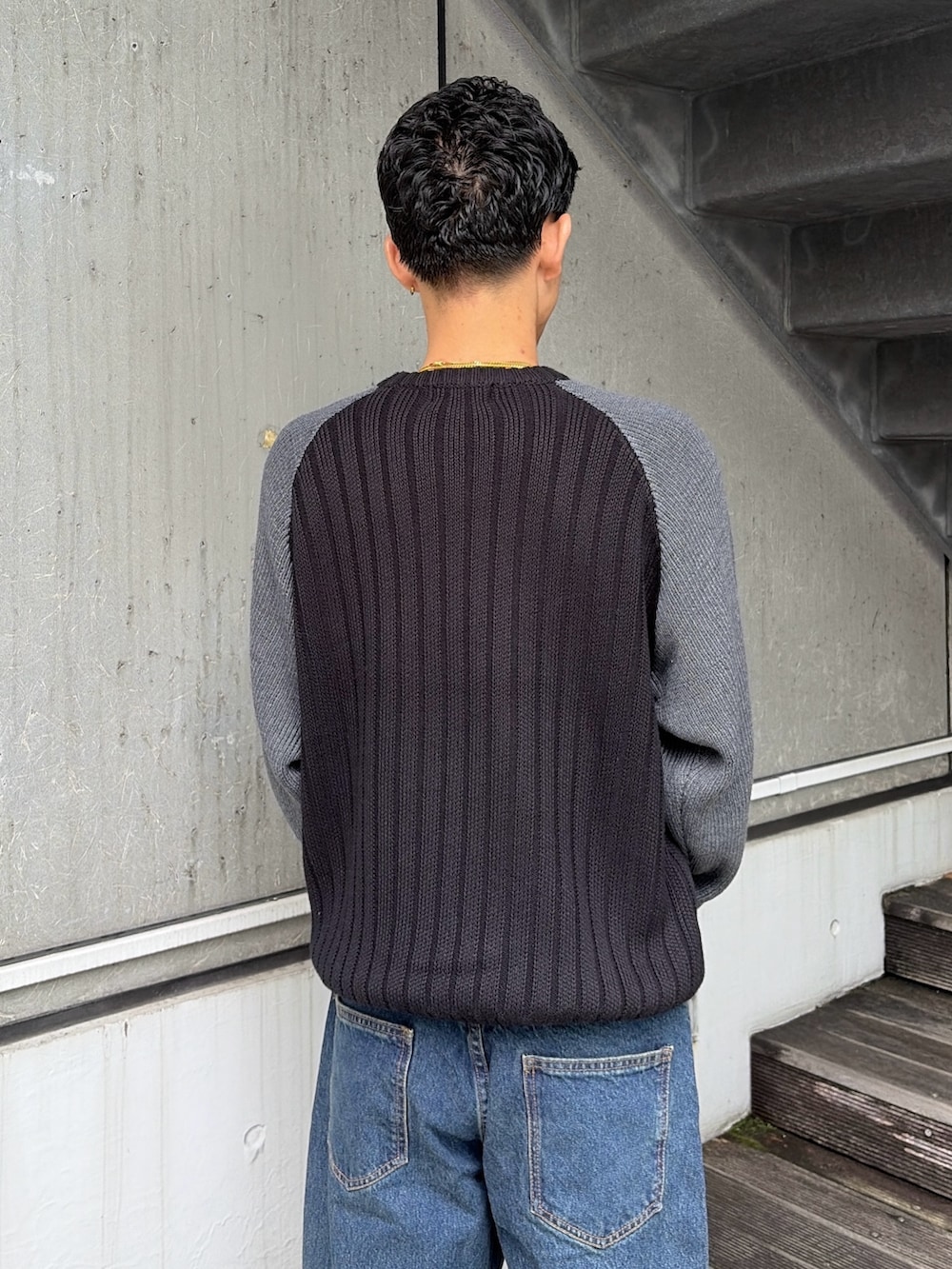ブラック系のニット/セーター、ブルー系のデニムパンツを着用したメンズの秋コーディネートの7枚目の写真