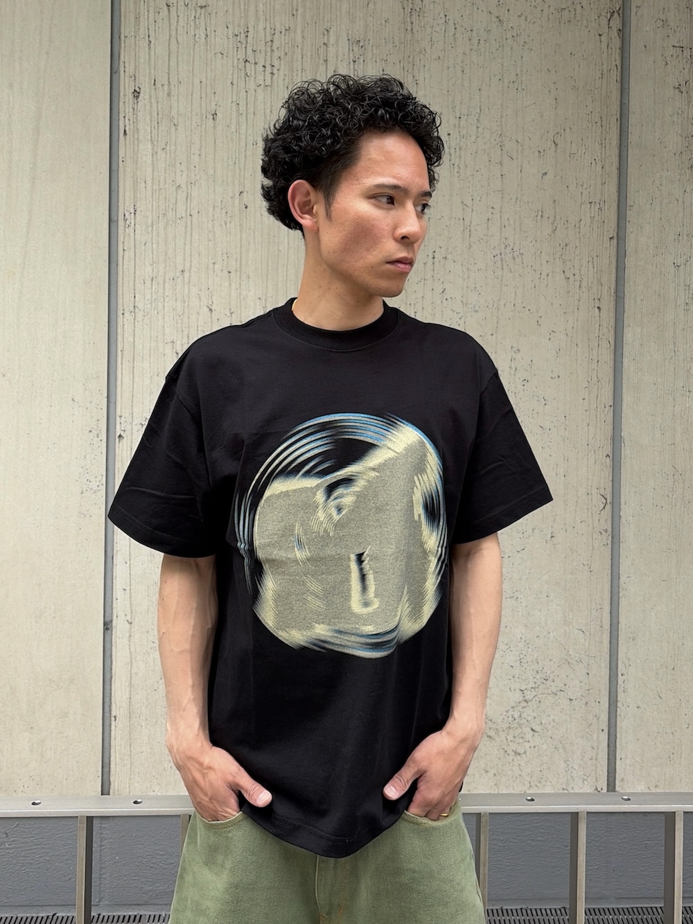 グリーン系のデニムパンツ、ブラック系のTシャツ/カットソーを着用したメンズの春コーディネートの5枚目の写真
