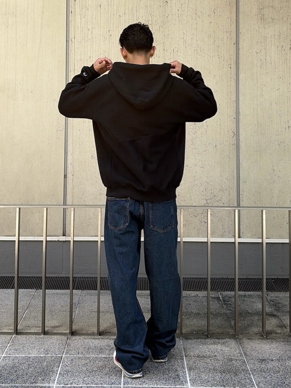 ブラック系のパーカー、ブラウン系のデニムパンツを着用したメンズの秋コーディネートの4枚目の写真