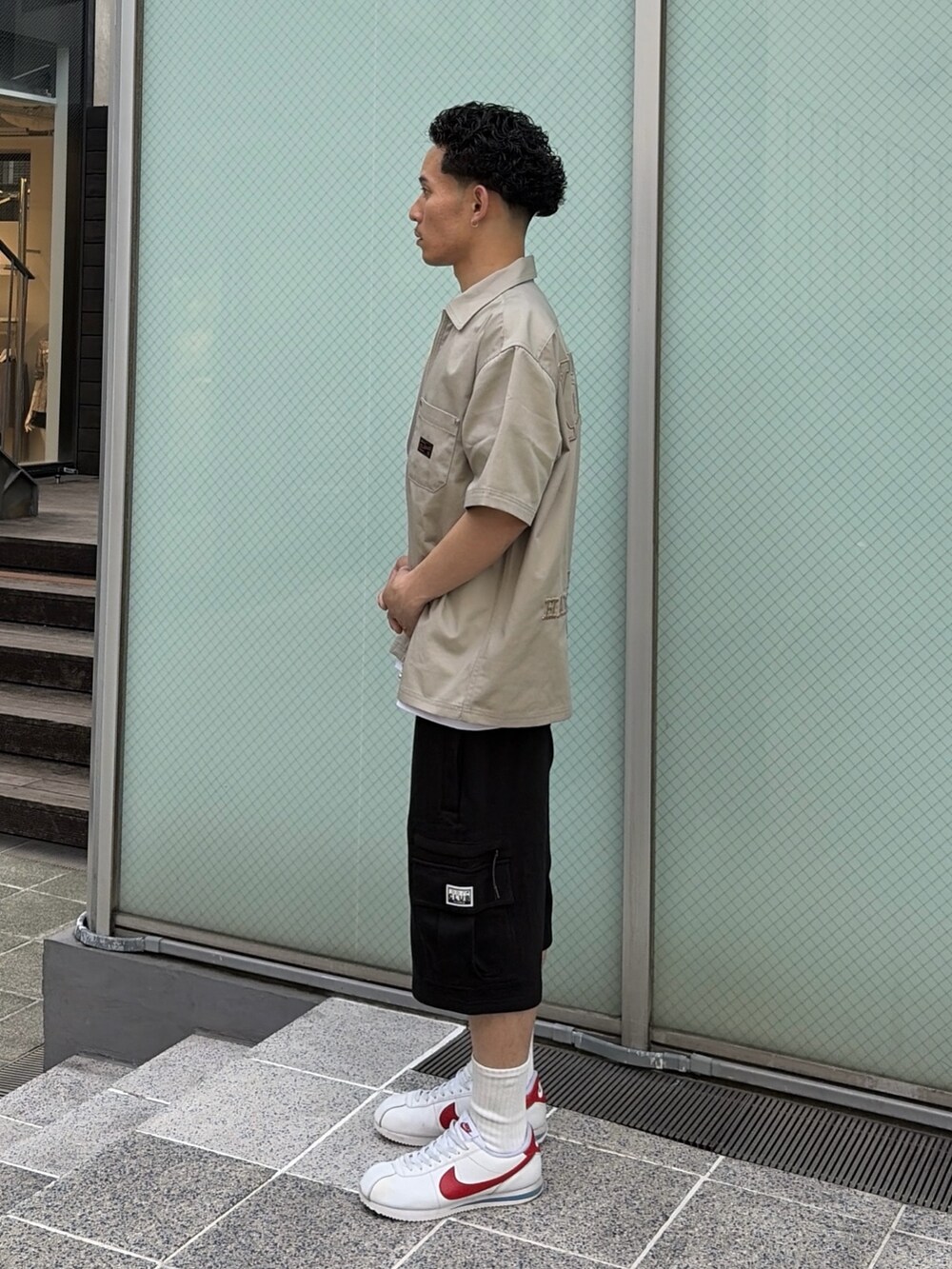 ブラック系のカーゴパンツ、グリーン系のシャツ/ブラウス、ホワイト系のTシャツ/カットソーを着用したメンズの春コーディネートの2枚目の写真