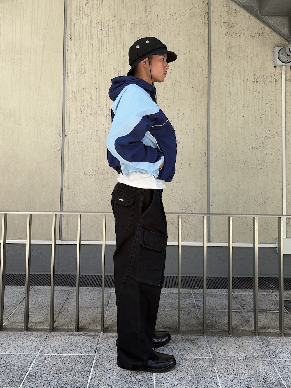 ブルー系のナイロンジャケット、ブラック系のカーゴパンツ、ブラック系のハットを着用したメンズの春コーディネートの3枚目の写真