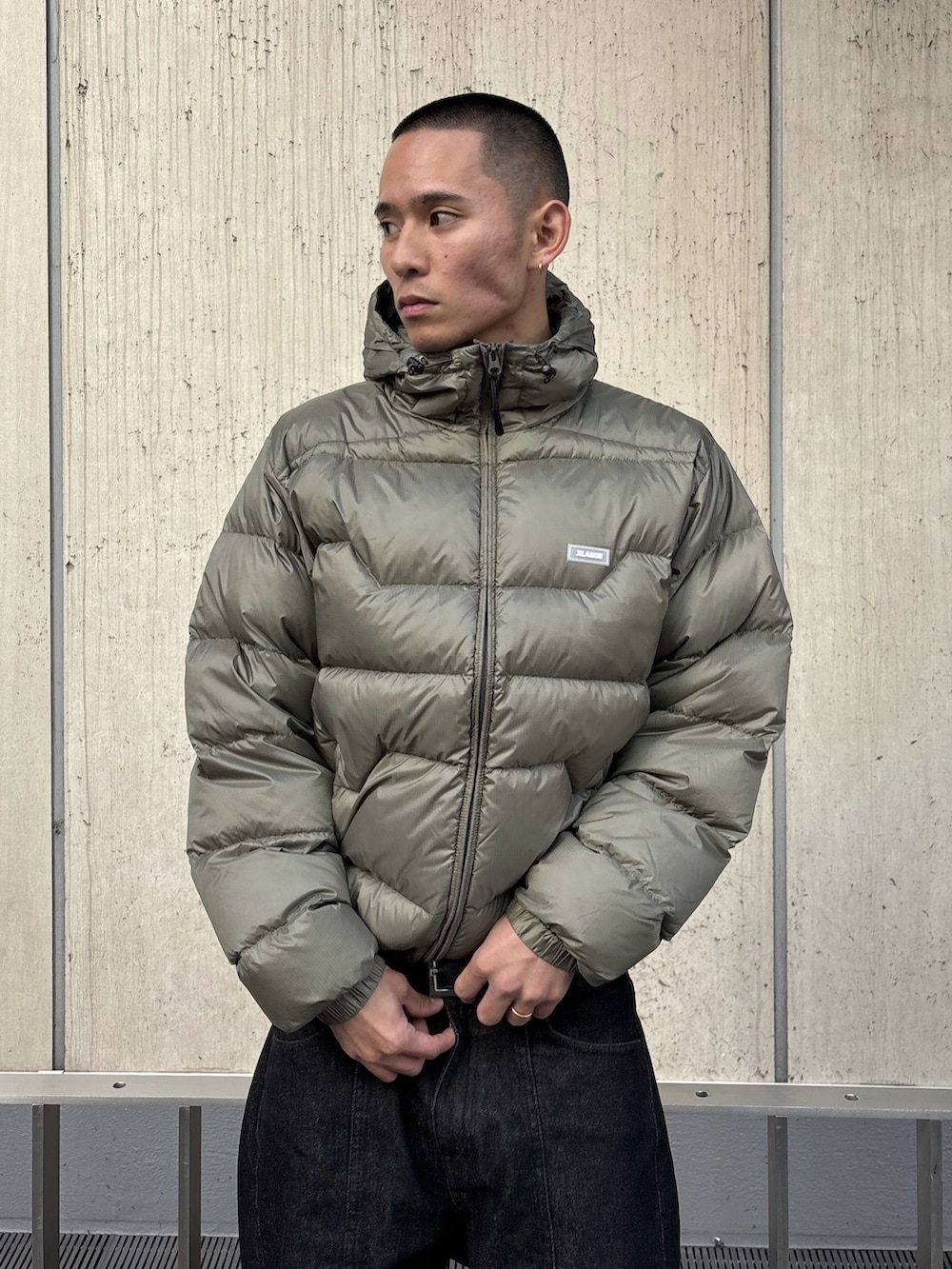 グリーン系のダウンジャケット/コート、ブラック系のデニムパンツを着用したメンズの秋コーディネートの5枚目の写真