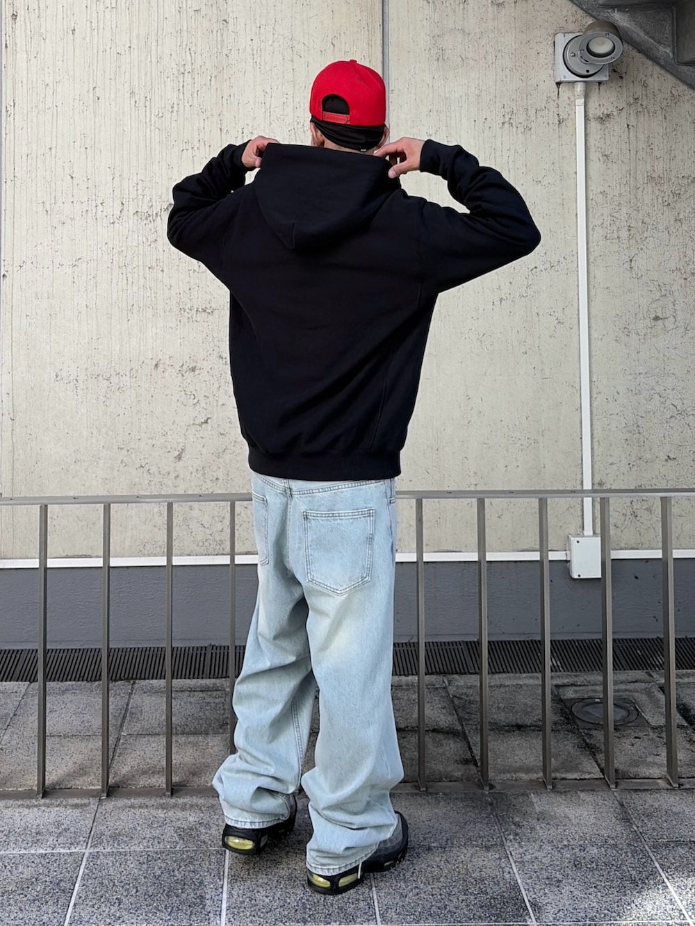 ブラック系のパーカー、ブルー系のデニムパンツ、レッド系のキャップを着用したメンズの秋コーディネートの5枚目の写真