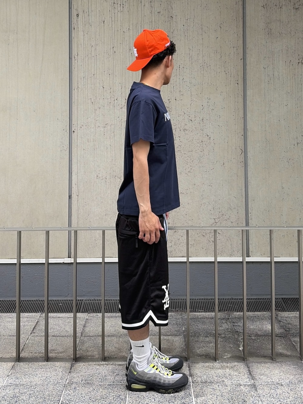 ブラック系のその他パンツ、ブルー系のTシャツ/カットソー、オレンジ系のキャップを着用したメンズの夏コーディネートの4枚目の写真