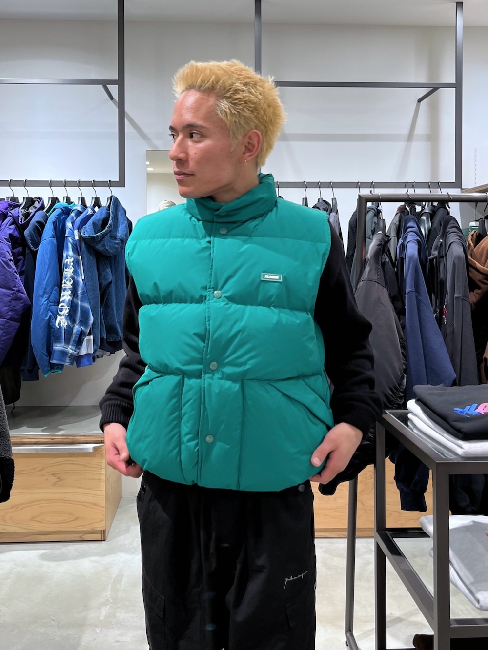 ブラック系のニット/セーター、グリーン系のダウンベスト、ブラック系のカーゴパンツを着用したメンズの秋コーディネートの5枚目の写真