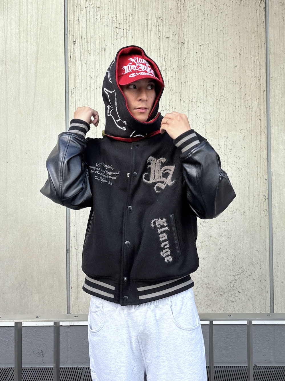 ブラック系のスタジャン、グレー系のスウェットパンツ、レッド系のキャップを着用したメンズの秋コーディネートの4枚目の写真