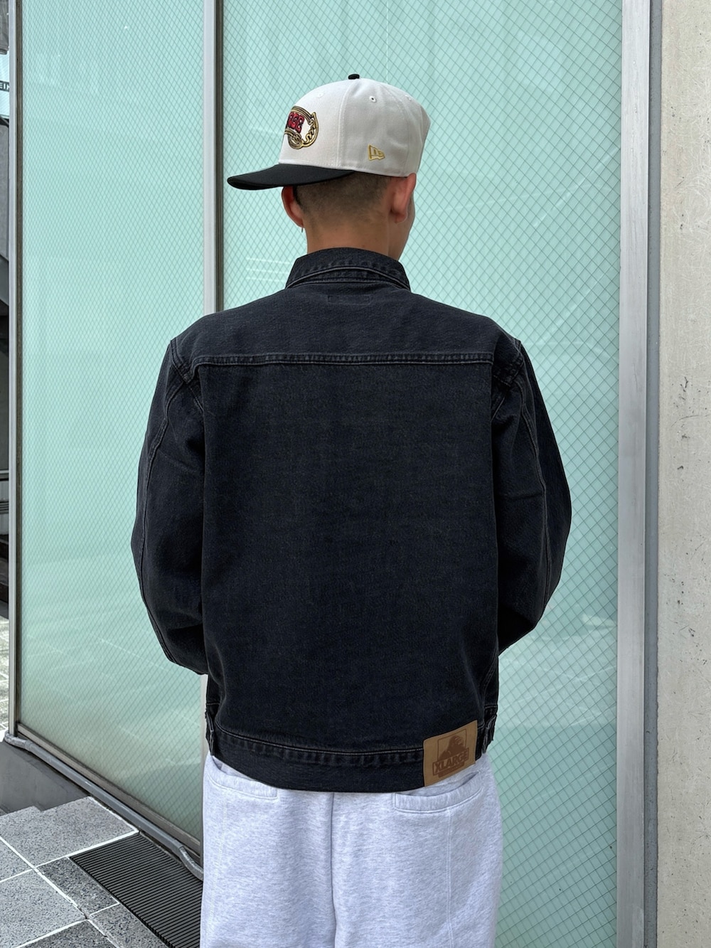 ブラック系のデニムジャケット、グレー系のスウェットパンツ、ホワイト系のキャップを着用したメンズの秋コーディネートの8枚目の写真