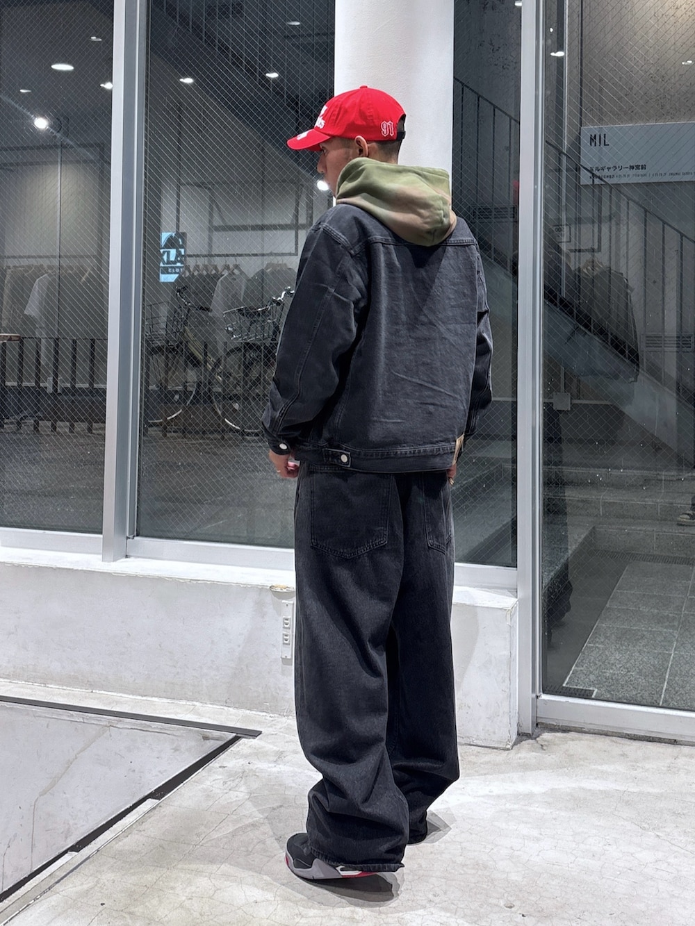 ブラック系のデニムジャケット、グリーン系のパーカー、ブラウン系のデニムパンツを着用したメンズの秋コーディネートの2枚目の写真