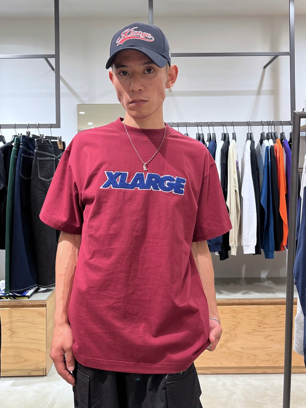 レッド系のTシャツ/カットソー、ブラック系のカーゴパンツ、ブルー系のキャップを着用したメンズの夏コーディネートの5枚目の写真