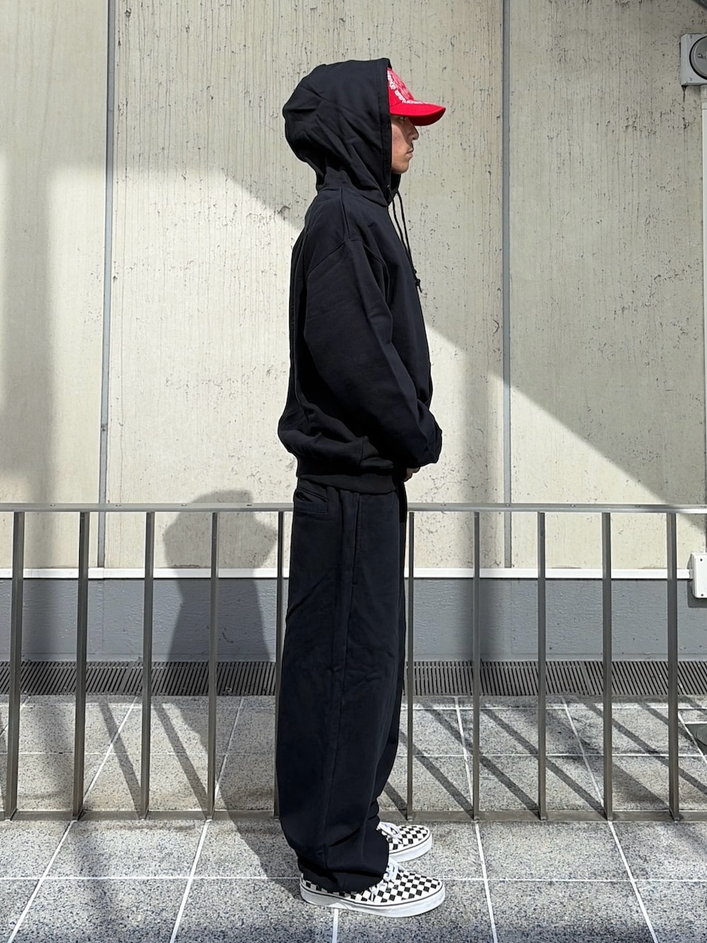 ブラック系のパーカー、ブラック系のその他パンツ、レッド系のキャップを着用したメンズの夏コーディネートの5枚目の写真