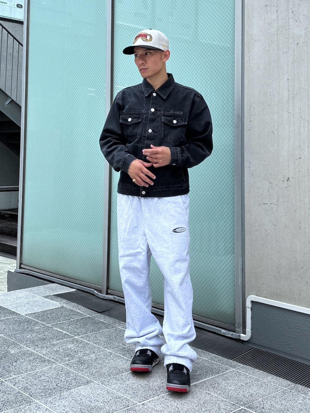 ブラック系のデニムジャケット、グレー系のスウェットパンツ、ホワイト系のキャップを着用したメンズの秋コーディネートの2枚目の写真