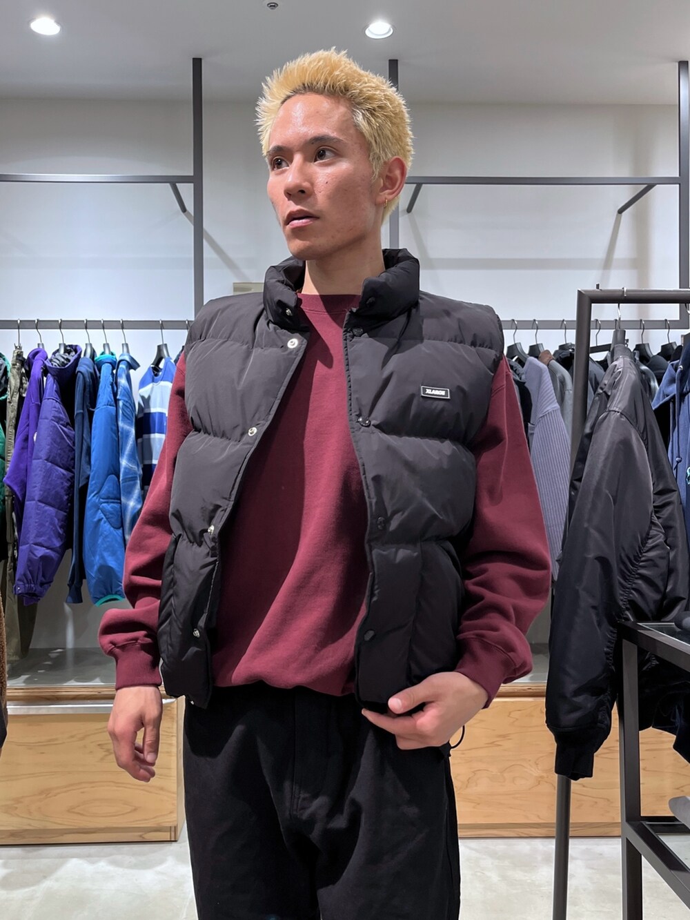 レッド系のスウェット、ブラック系のその他パンツ、ブラック系のダウンベストを着用したメンズの秋コーディネートの9枚目の写真