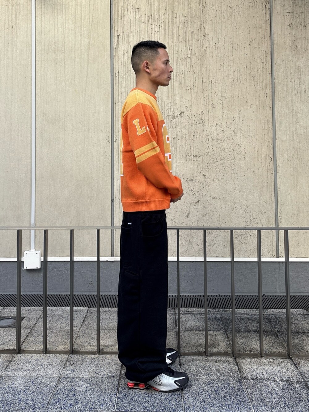 オレンジ系のニット/セーター、グレー系のスウェットパンツを着用したメンズの冬コーディネートの3枚目の写真