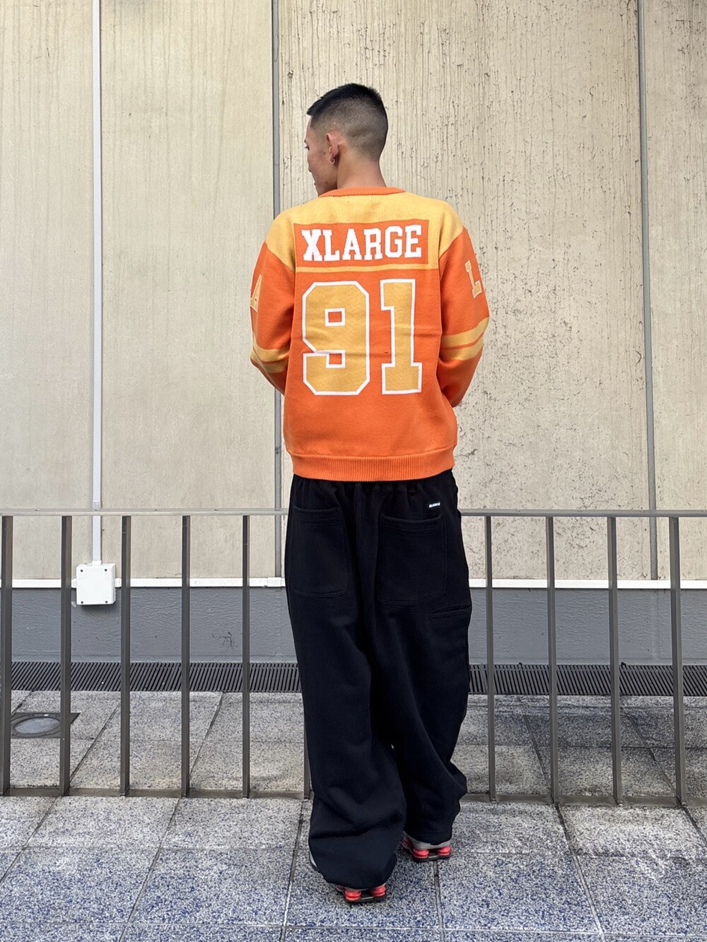 オレンジ系のニット/セーター、グレー系のスウェットパンツを着用したメンズの冬コーディネートの4枚目の写真