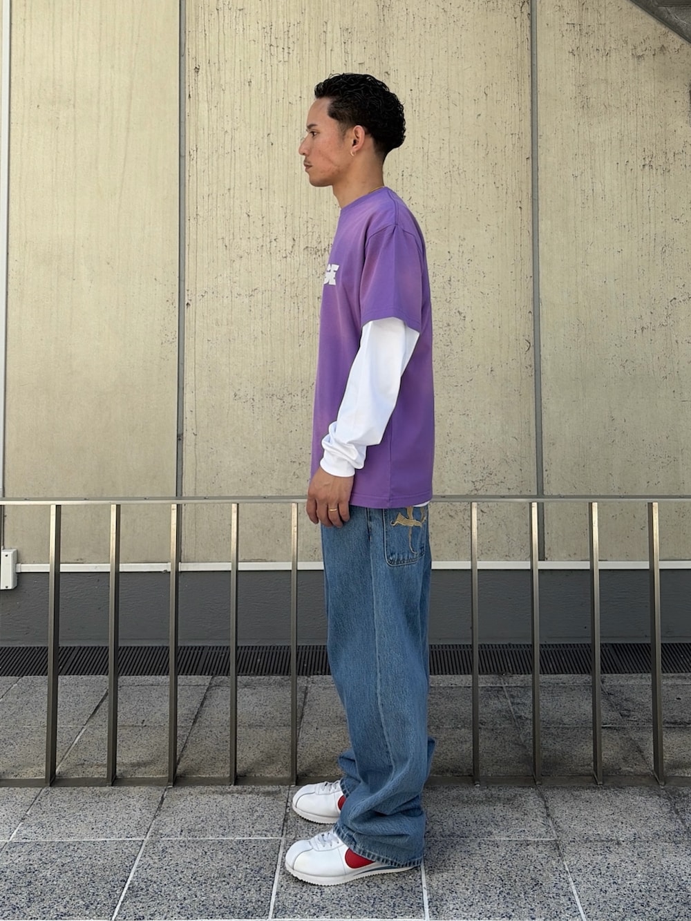 パープル系のTシャツ/カットソー、ホワイト系のTシャツ/カットソー、ブルー系のデニムパンツを着用したメンズの春コーディネートの2枚目の写真