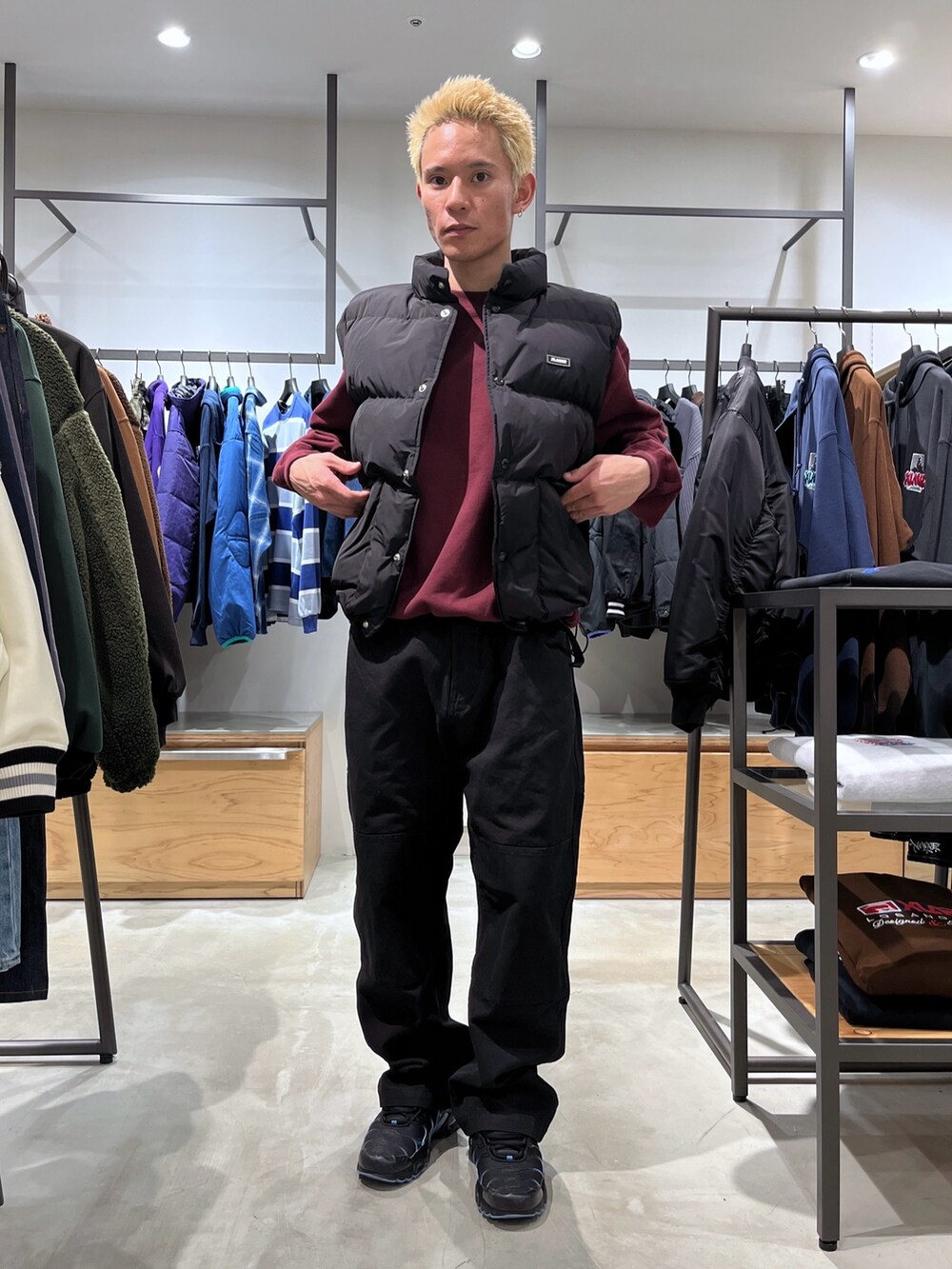 レッド系のスウェット、ブラック系のその他パンツ、ブラック系のダウンベストを着用したメンズの秋コーディネートの7枚目の写真