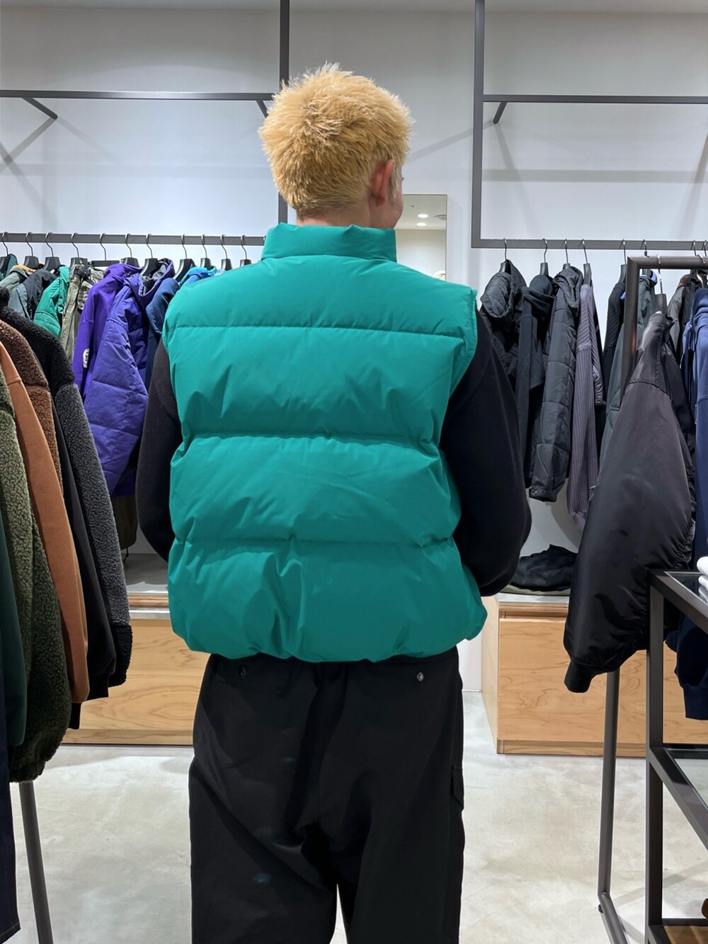 ブラック系のニット/セーター、グリーン系のダウンベスト、ブラック系のカーゴパンツを着用したメンズの秋コーディネートの7枚目の写真