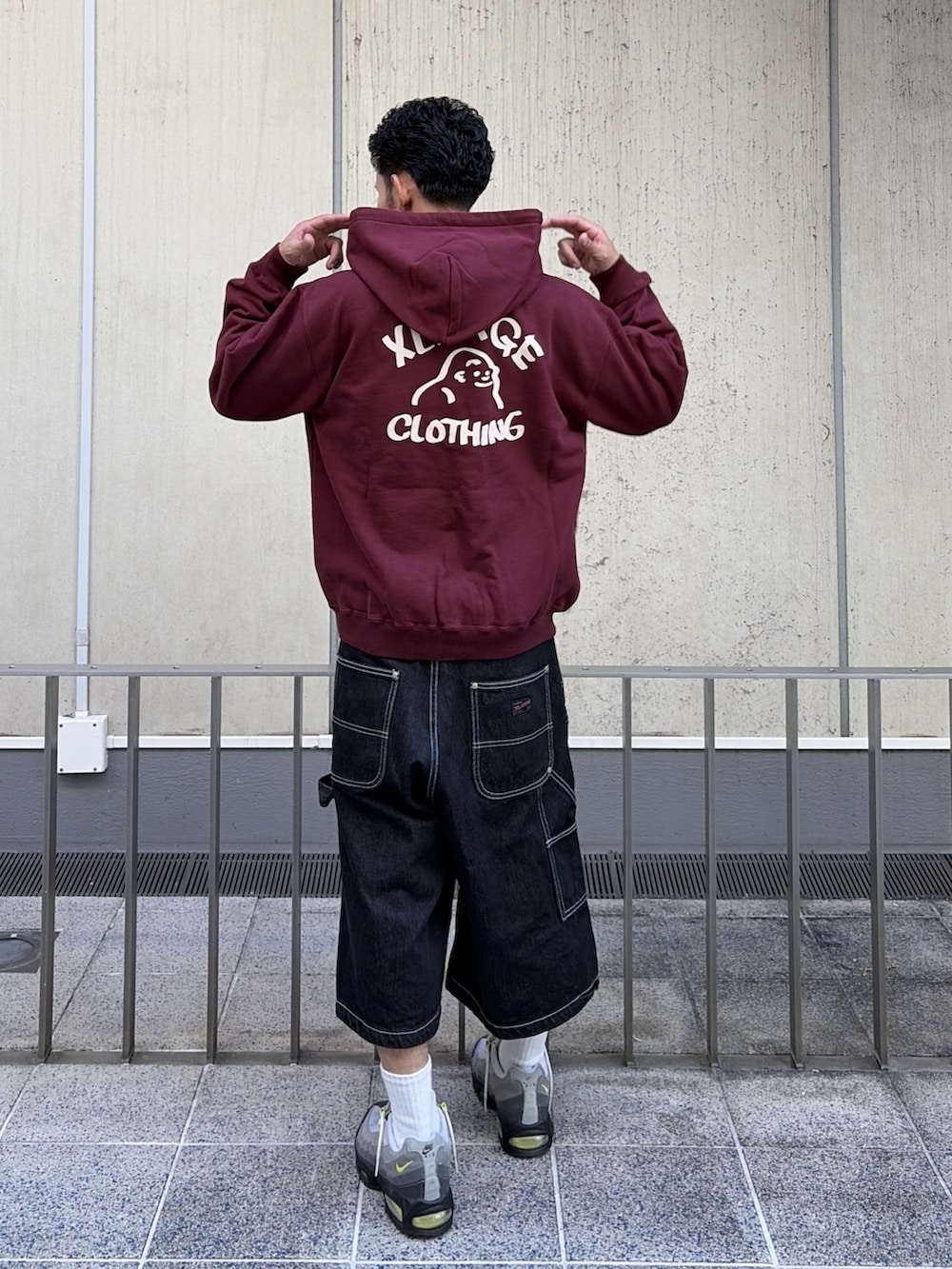 レッド系のパーカー、ブラック系のデニムパンツを着用したメンズの秋コーディネートの7枚目の写真