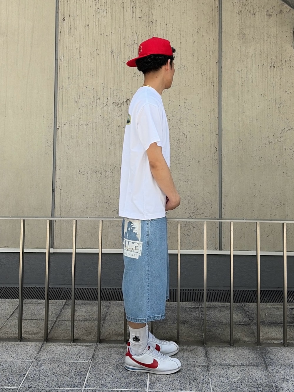 グリーン系のデニムパンツ、ホワイト系のTシャツ/カットソー、レッド系のキャップを着用したメンズの春コーディネートの3枚目の写真
