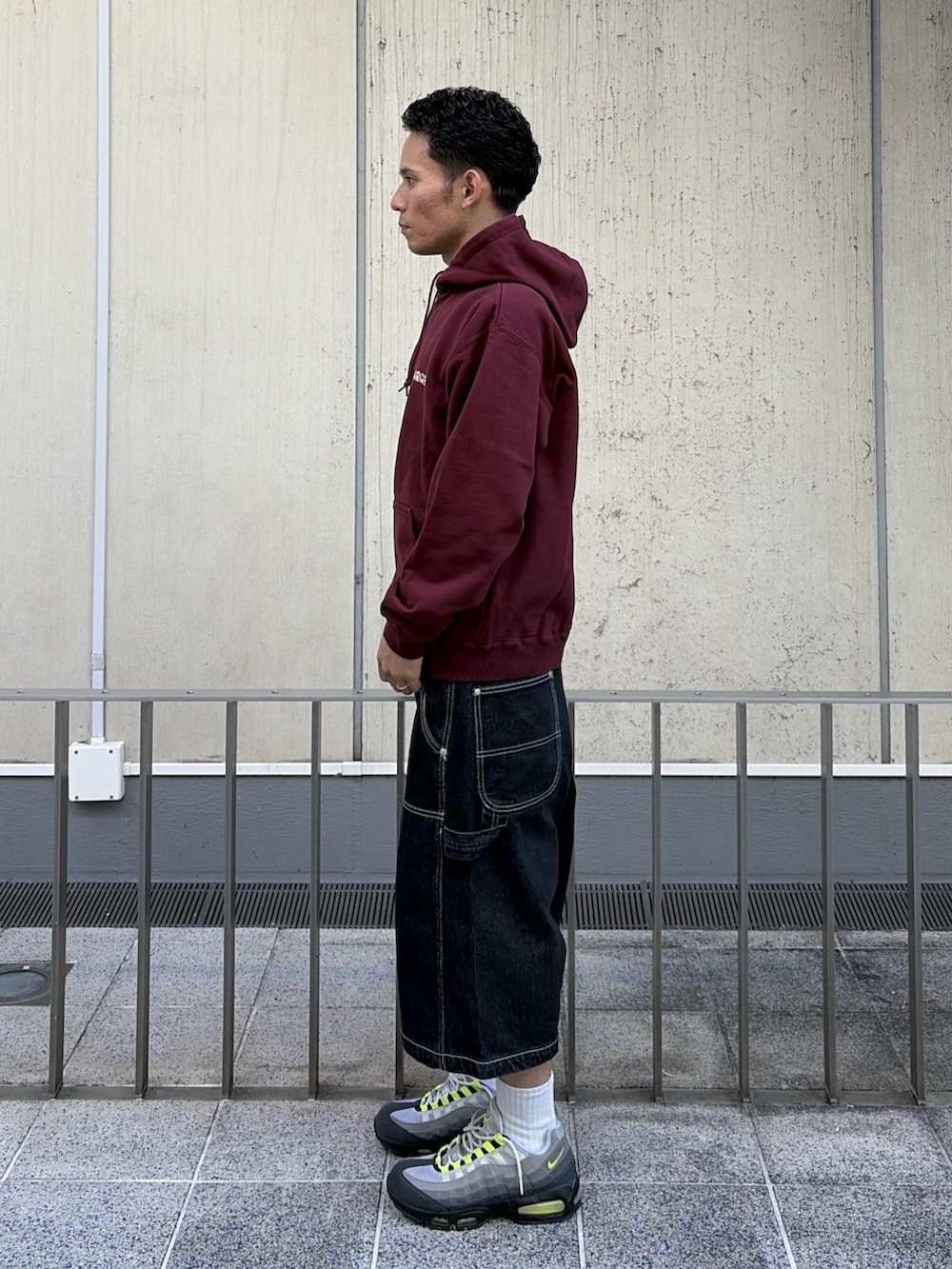 レッド系のパーカー、ブラック系のデニムパンツを着用したメンズの秋コーディネートの8枚目の写真