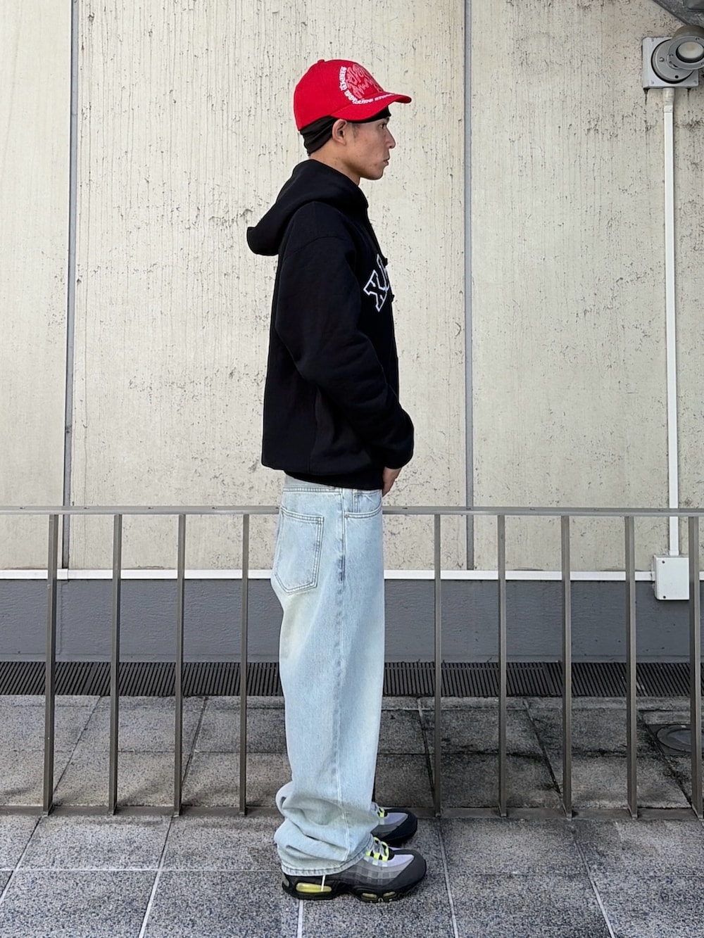 ブラック系のパーカー、ブルー系のデニムパンツ、レッド系のキャップを着用したメンズの秋コーディネートの4枚目の写真
