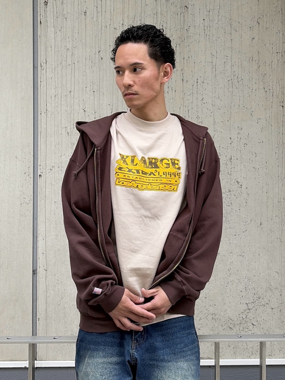 ベージュ系のTシャツ/カットソー、ブラウン系のパーカー、ブルー系のデニムパンツを着用したメンズの春コーディネートの6枚目の写真