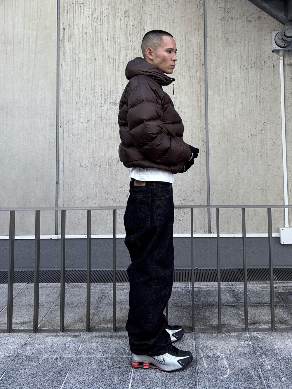 ブラウン系のダウンジャケット/コート、ブラック系のデニムパンツ、ブラック系の手袋を着用したメンズの秋コーディネートの3枚目の写真