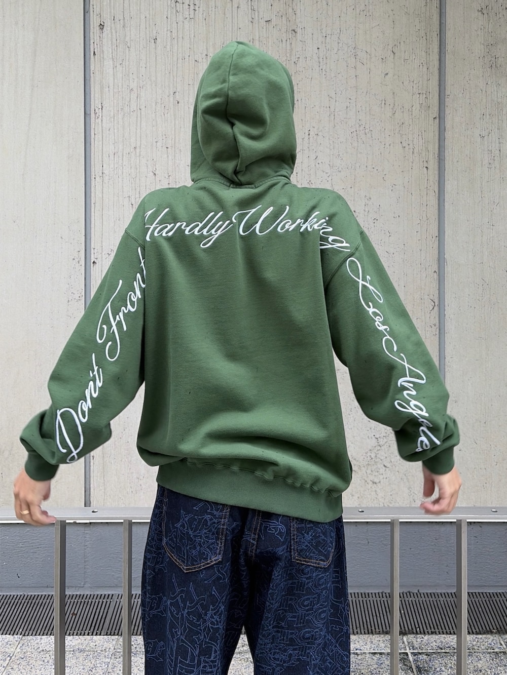 グリーン系のパーカー、ブルー系のデニムパンツ、レッド系のニットキャップ/ビーニーを着用したメンズの秋コーディネートの8枚目の写真