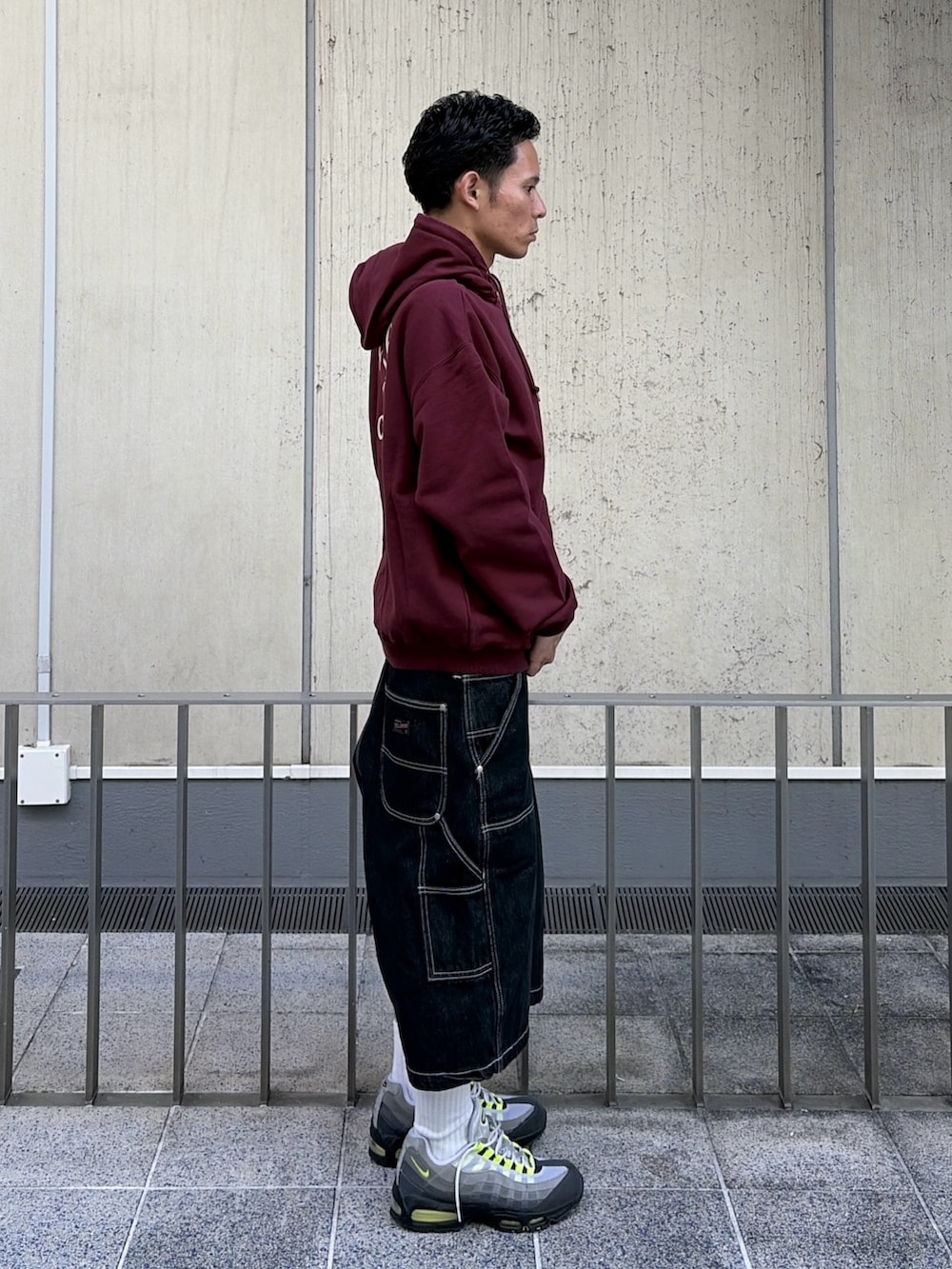 レッド系のパーカー、ブラック系のデニムパンツを着用したメンズの秋コーディネートの6枚目の写真