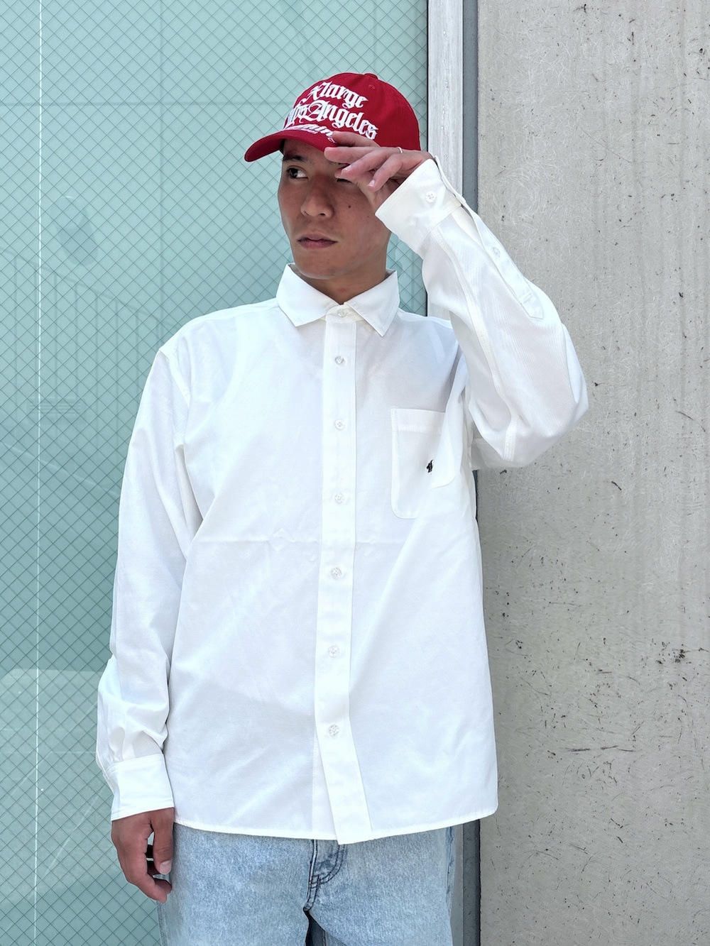 ブルー系のデニムパンツ、ホワイト系のシャツ/ブラウス、レッド系のキャップを着用したメンズの秋コーディネートの5枚目の写真