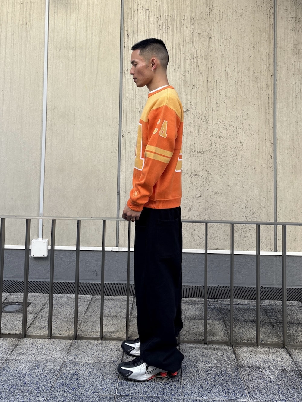 オレンジ系のニット/セーター、グレー系のスウェットパンツを着用したメンズの冬コーディネートの2枚目の写真