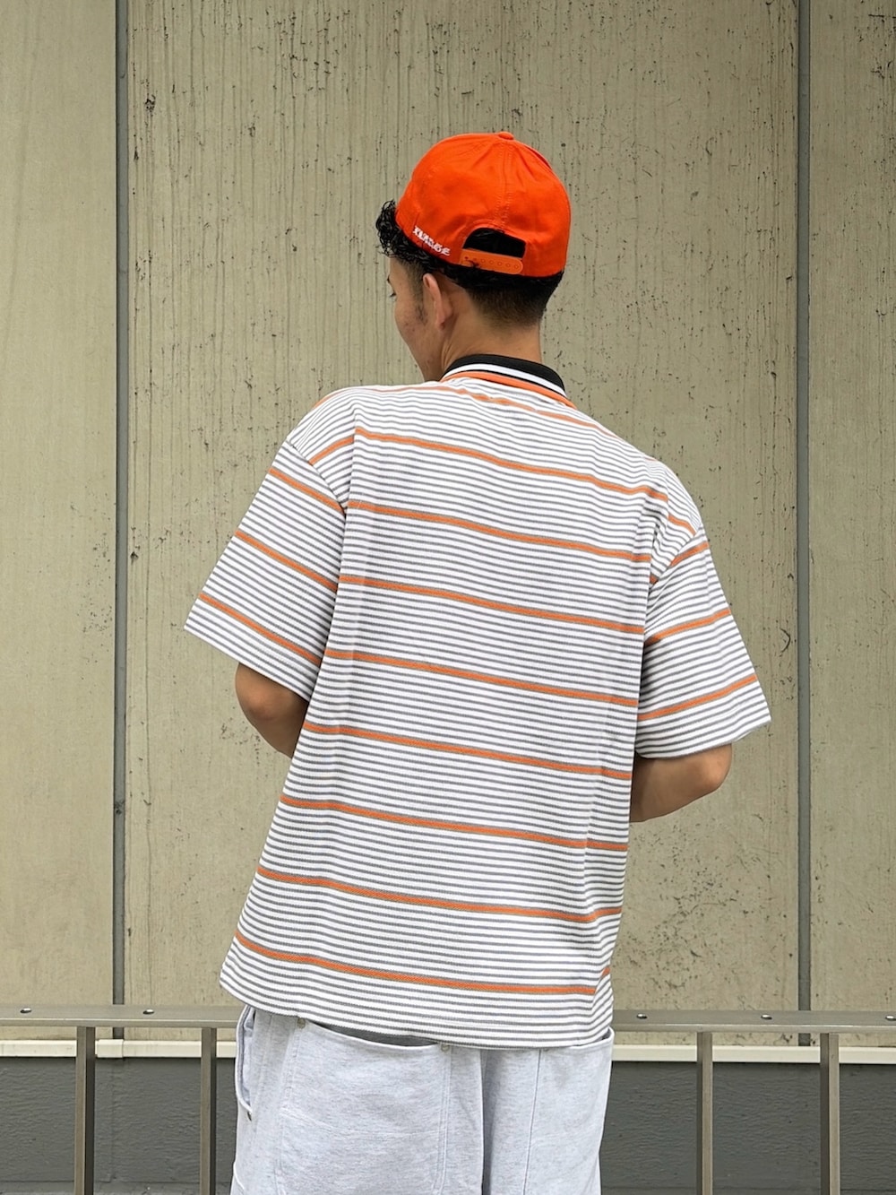 グレー系のスウェットパンツ、グレー系のTシャツ/カットソー、オレンジ系のキャップを着用したメンズの夏コーディネートの7枚目の写真