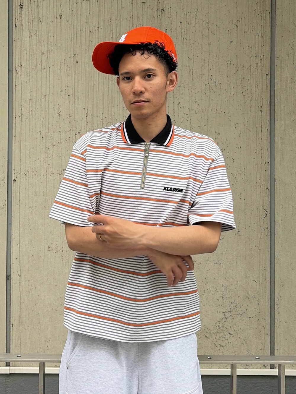グレー系のスウェットパンツ、グレー系のTシャツ/カットソー、オレンジ系のキャップを着用したメンズの夏コーディネートの5枚目の写真