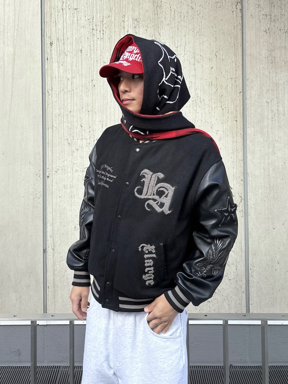 ブラック系のスタジャン、グレー系のスウェットパンツ、レッド系のキャップを着用したメンズの秋コーディネートの6枚目の写真