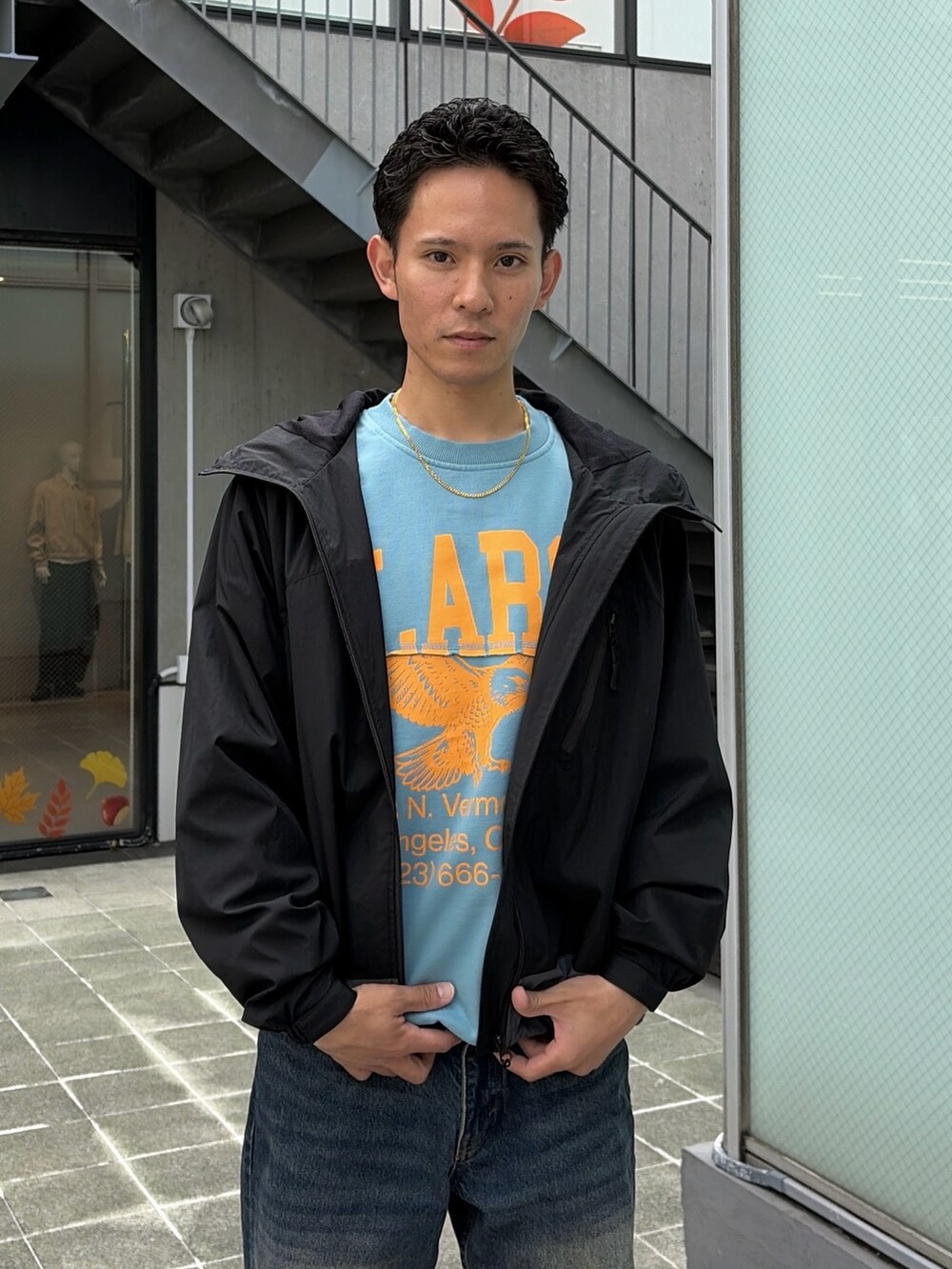 レッド系のナイロンジャケット、グレー系のスウェット、ブルー系のデニムパンツを着用したメンズの秋コーディネートの6枚目の写真