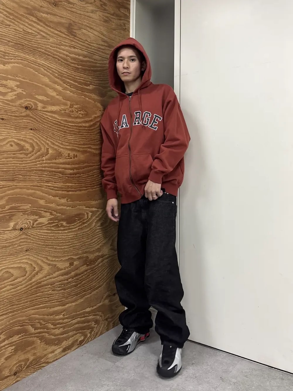 レッド系のパーカー、ブラック系のデニムパンツを着用したメンズの冬コーディネートの2枚目の写真