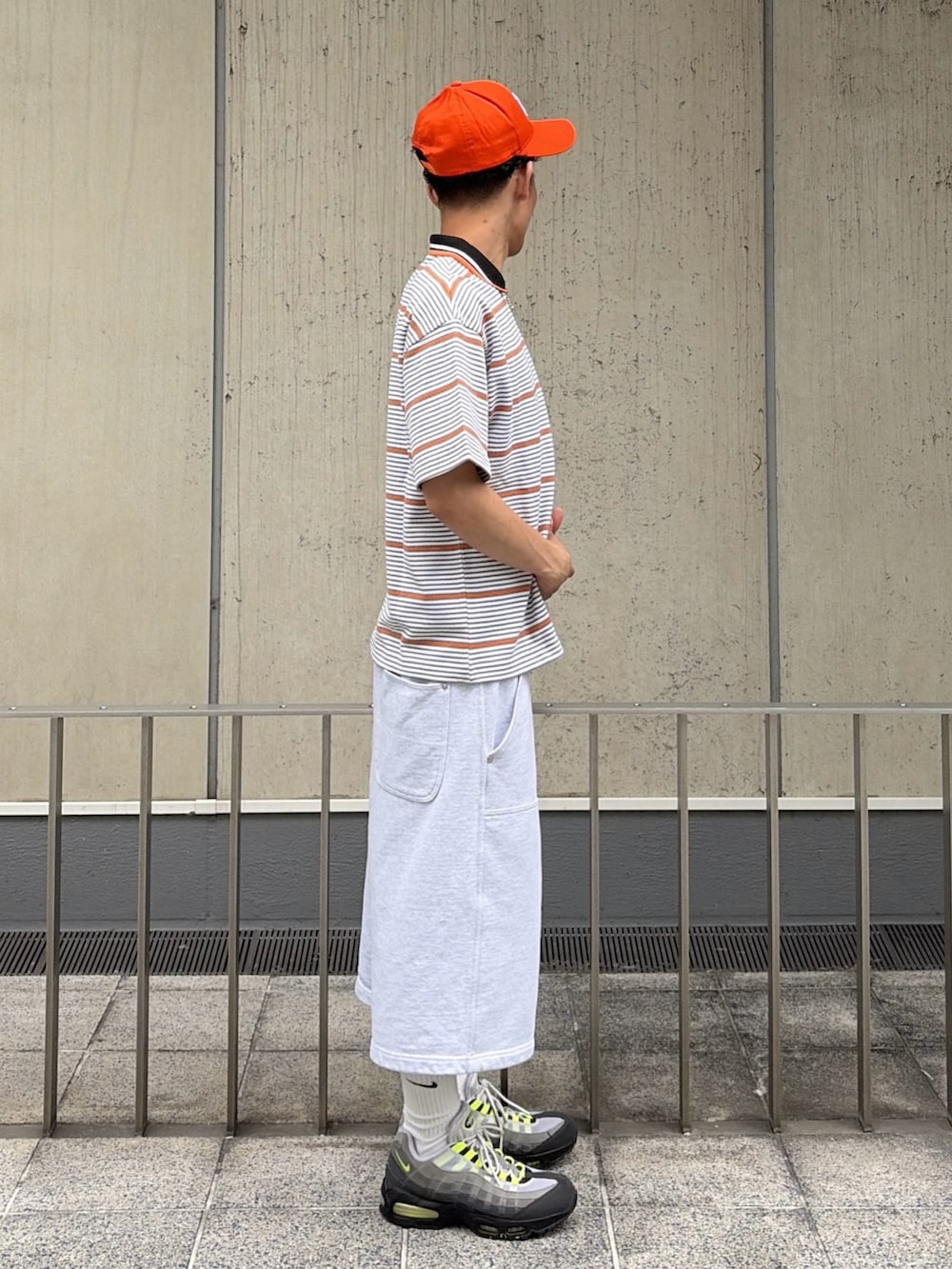 グレー系のスウェットパンツ、グレー系のTシャツ/カットソー、オレンジ系のキャップを着用したメンズの夏コーディネートの3枚目の写真