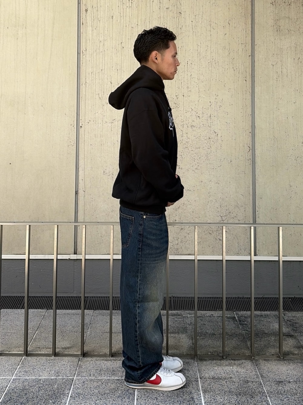 ブラック系のパーカー、ブラウン系のデニムパンツを着用したメンズの秋コーディネートの3枚目の写真