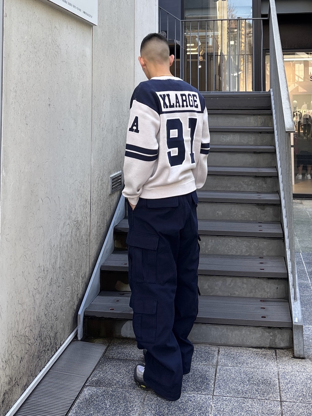 オレンジ系のニット/セーター、ブルー系のカーゴパンツを着用したメンズの冬コーディネートの3枚目の写真