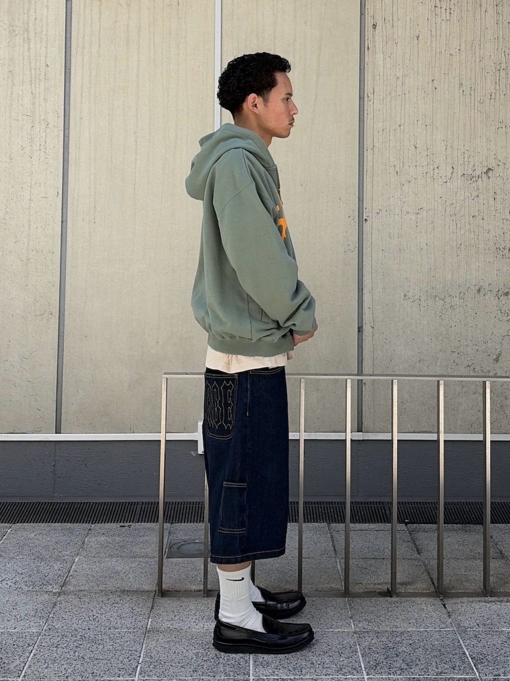 ピンク系のパーカー、ブルー系のデニムパンツを着用したメンズの春コーディネートの4枚目の写真