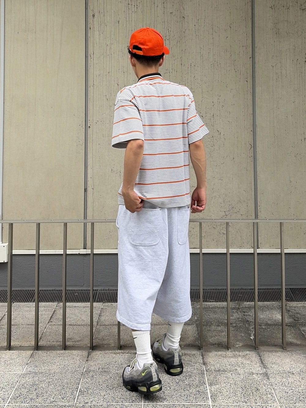 グレー系のスウェットパンツ、グレー系のTシャツ/カットソー、オレンジ系のキャップを着用したメンズの夏コーディネートの4枚目の写真